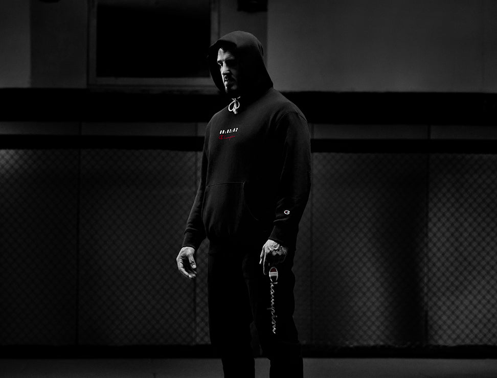Person wearing a black hoodie with a logo in a dark room