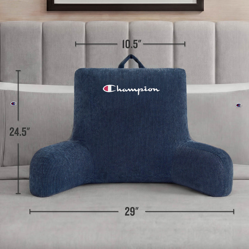 A Champion Corduroy Backrest Pillow with arms, featuring a soft blue corduroy cover and the embroidered Champion logo, sits on a bed. The pillow measures 24.5 inches tall, 29 inches wide, and 10.5 inches deep.