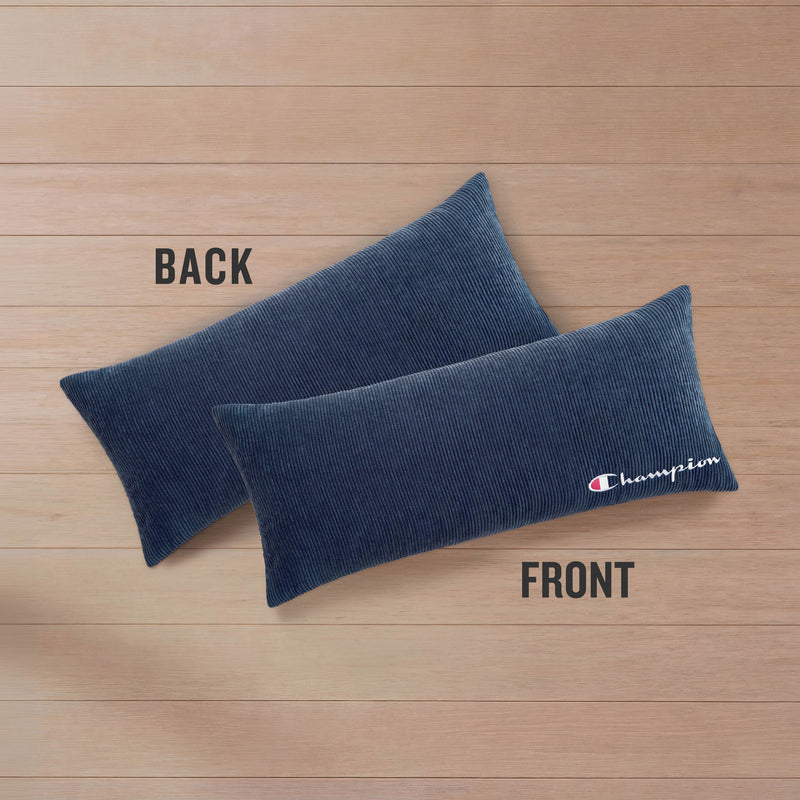 Two Champion Corduroy Body Pillows are displayed on a wooden surface. One pillow is labeled BACK, while the other, labeled FRONT, showcases an embroidered Champion logo in white and red. Designed by Champion, these pillows bring both signature style and comfort to any lounging area.