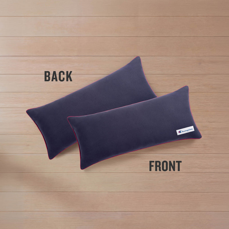 Two rectangular Champion Faux Wool Body Pillows in navy blue, featuring accent red trim, are displayed on a wooden surface. The pillow labeled "FRONT" has a small white Champion label, while the one labeled "BACK" is plain.
