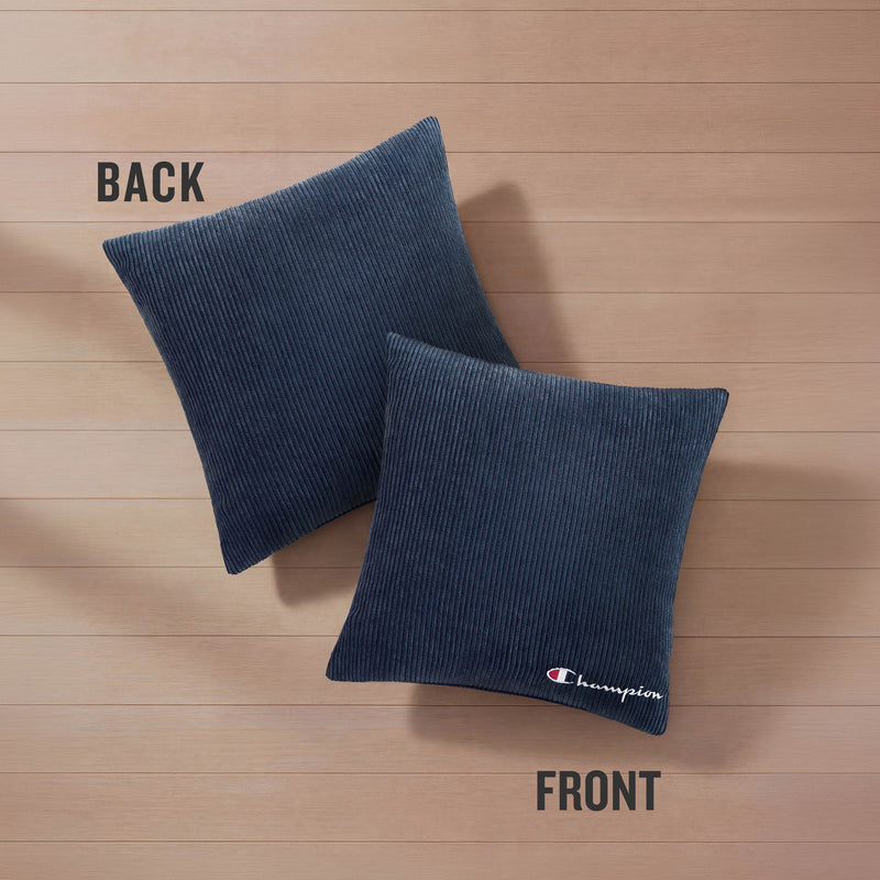 Two Champion 18" x 18" Logo Pillows by Champion, featuring a dark blue corduroy polyester cover, rest on a wooden floor. The pillow labeled "FRONT" displays a small embroidered Champion logo in the corner, while the "BACK" pillow is plain.