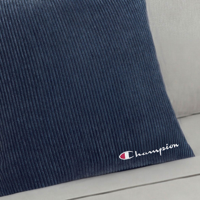 The Champion 18" x 18" Logo Pillow features a blue corduroy design with the Champion logo and name embroidered in white and red, making it a stylish addition to any space.