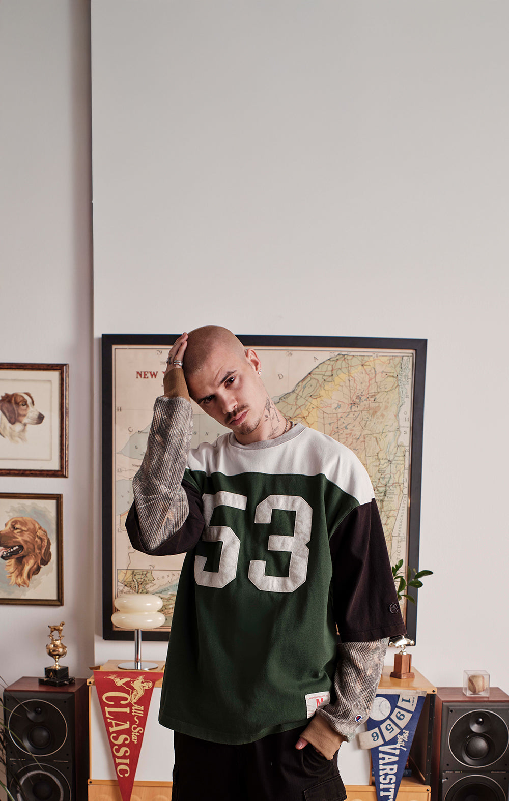 Person wearing a green and white sweatshirt with the number 53, standing in a room with decor elements.