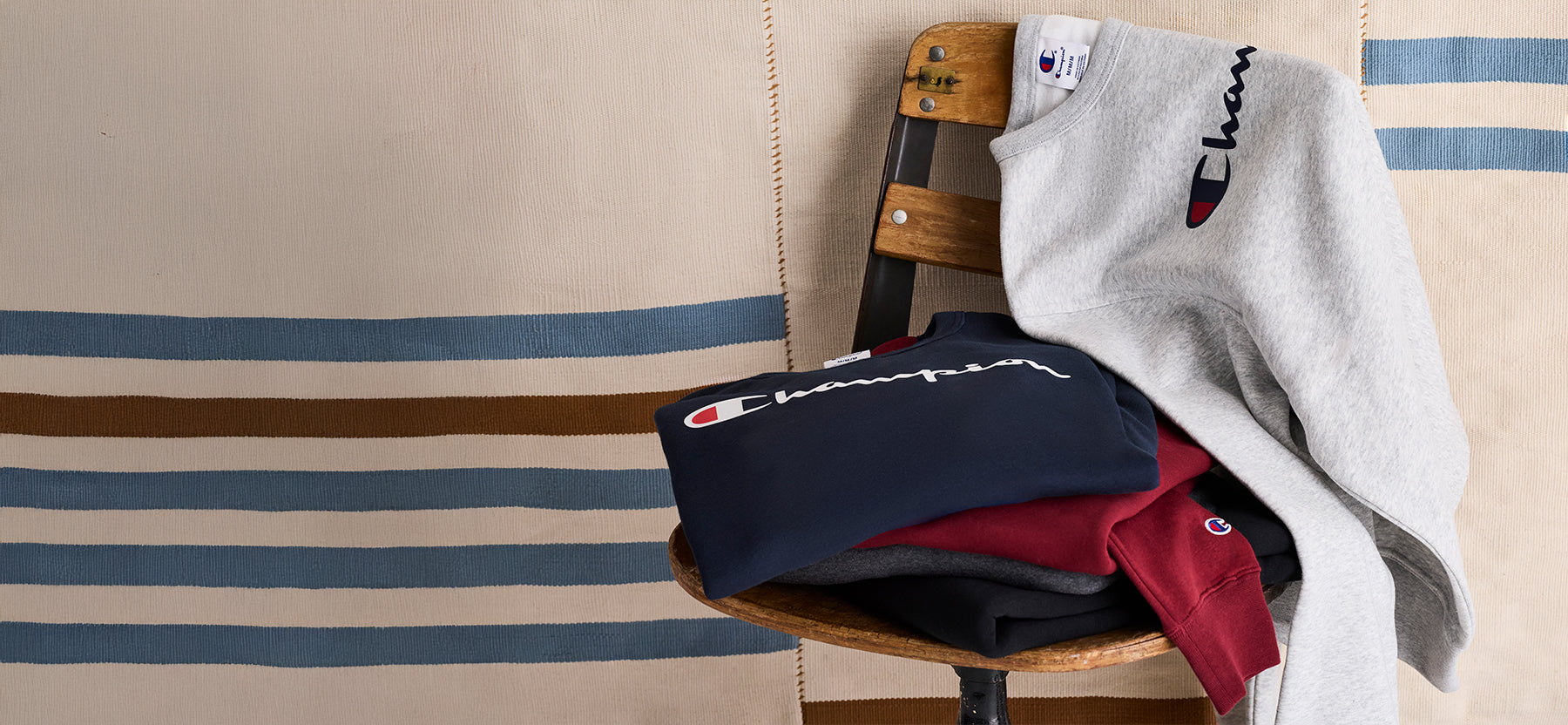 Chair with folded clothes and a sweatshirt on a striped background