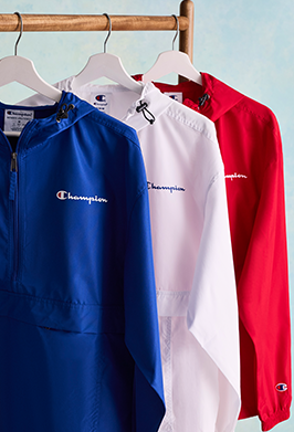 Three jackets in blue, white, and red hanging on a rack with Champion logo.
