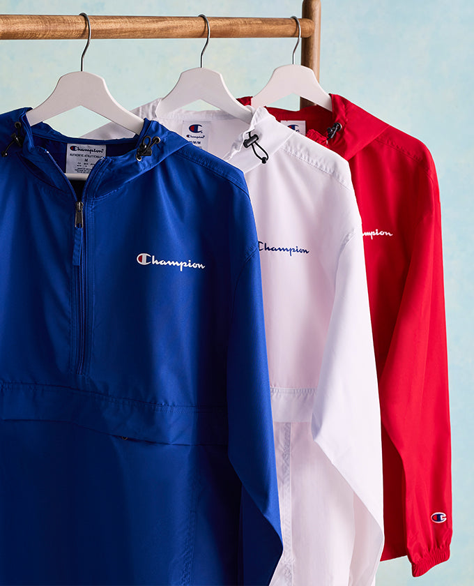 Three jackets in blue, white, and red hanging on a rack with Champion logo.