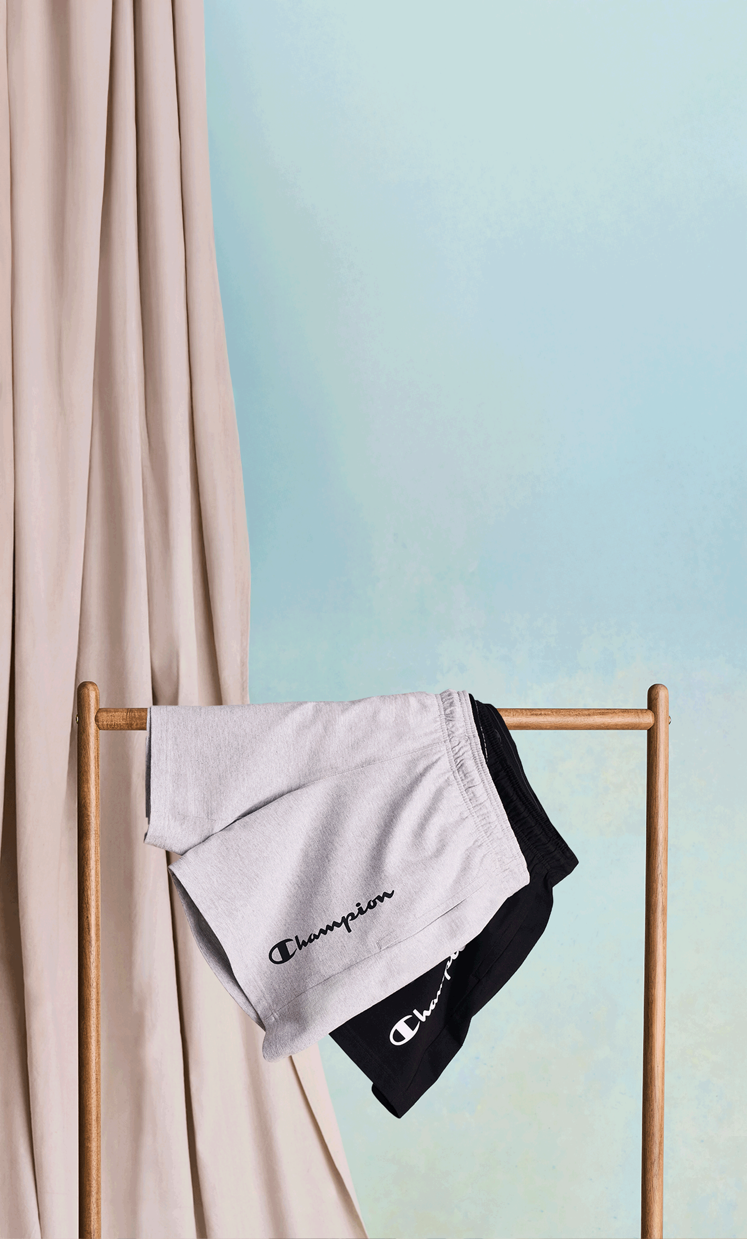 Animated GIF of multiple pairs of shorts hanging from a clothing rack against a blue background.