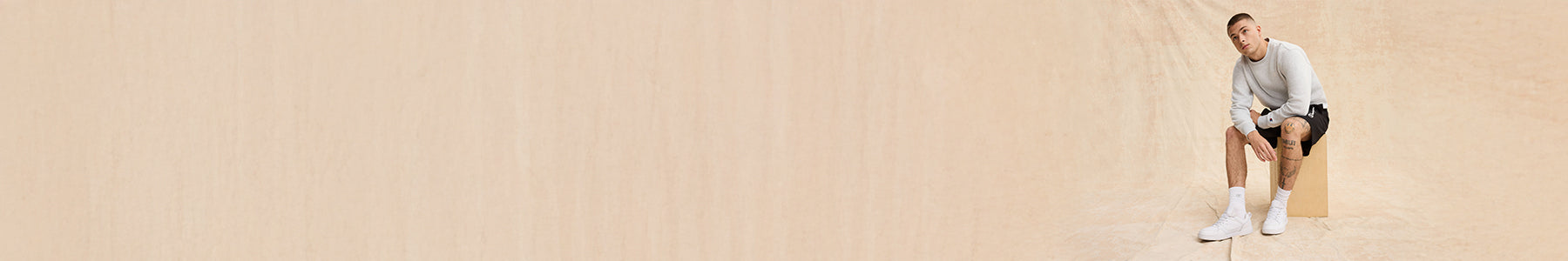Person sitting on a box against a beige background