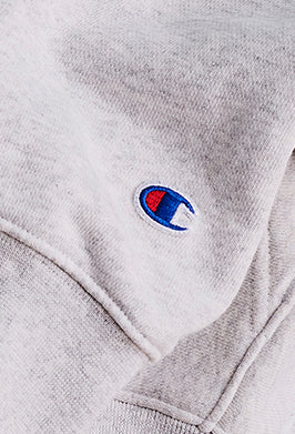 Close-up of a gray hoodie with a Champion logo on the chest.