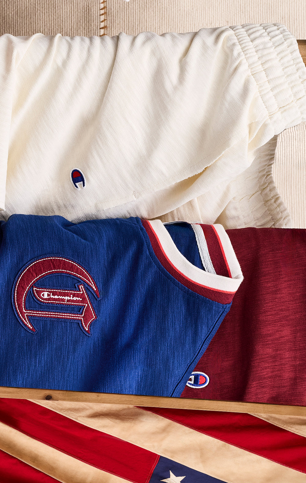 Collection of Champion branded clothing items including shorts and a jersey on a wooden surface with an American flag.