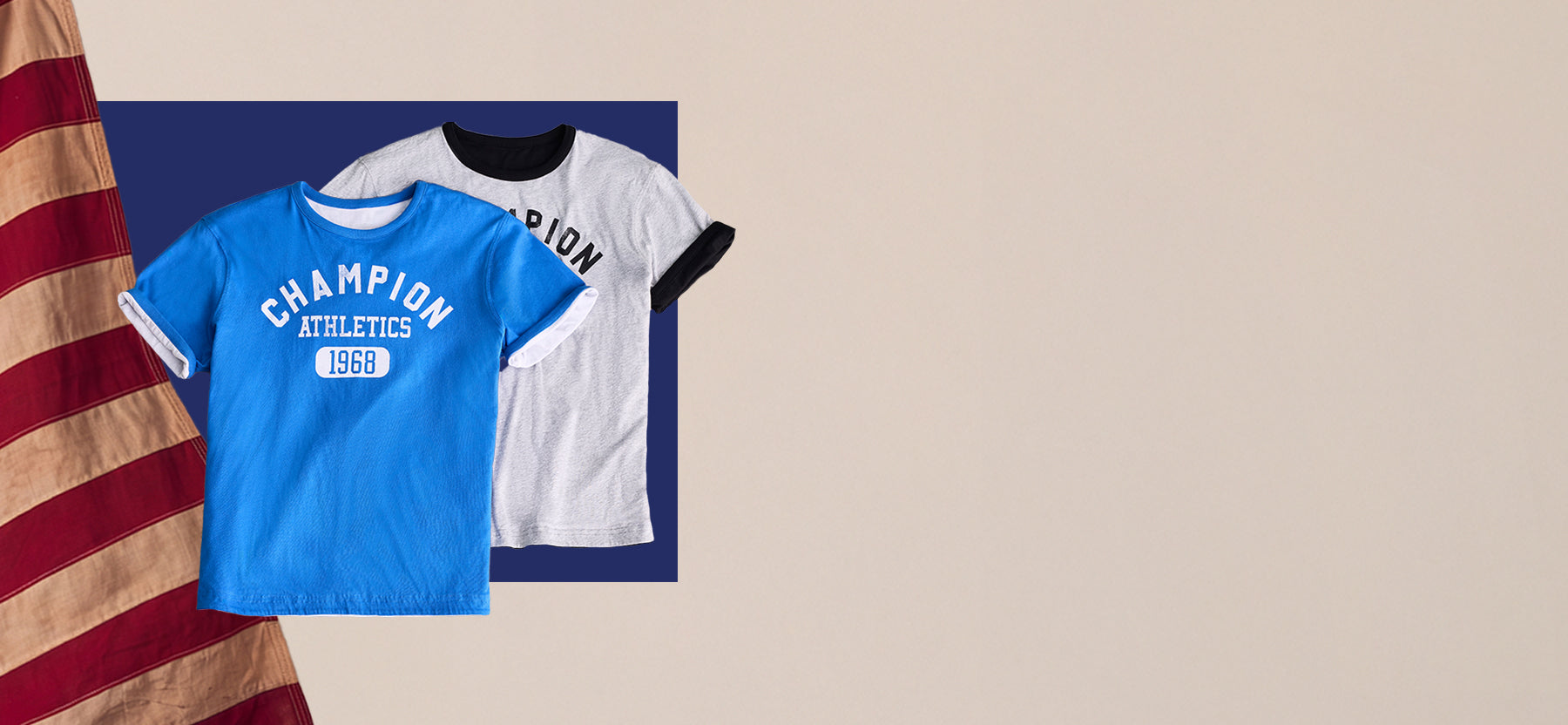 Two Champion athletic t-shirts displayed against a dark blue rectangular backdrop on a beige background, with a distressed American flag graphic on the left. One shirt is bright blue with white lettering reading 'CHAMPION ATHLETICS 1969,' and the other is white with black ringer-style trim and black lettering.