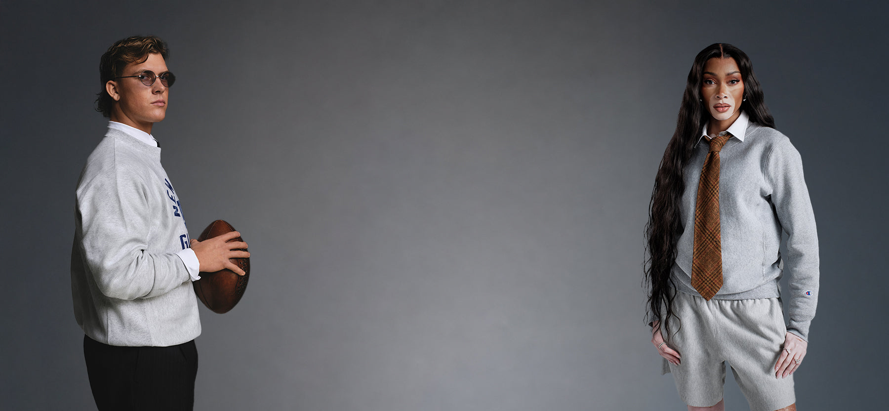 Two models posing in matching gray athletic tracksuits, one holding a football on the left and the other wearing a brown patterned tie on the right, set against a solid dark gray studio background.
