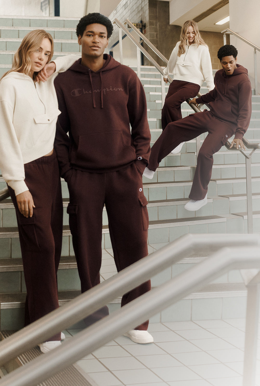 Man and women in chocolate brown and cream champion hoodie set. On stairls in a building