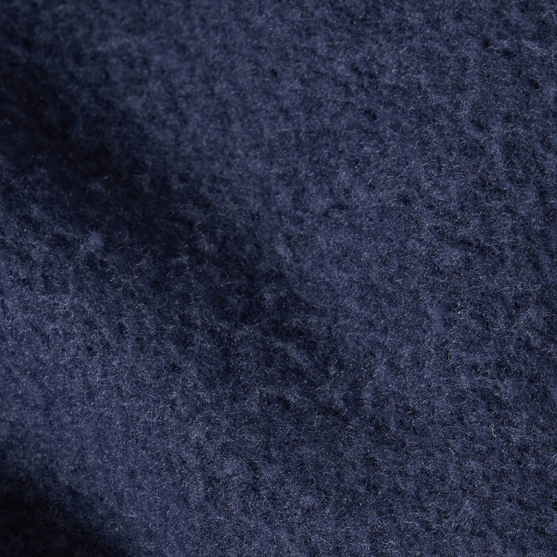Close-up of dark blue textured fabric with visible fibers and subtle shadowing, showcasing the premium look and feel of a heavyweight fleece from the Champion Women’s Knitted Hooded Sweatshirt.