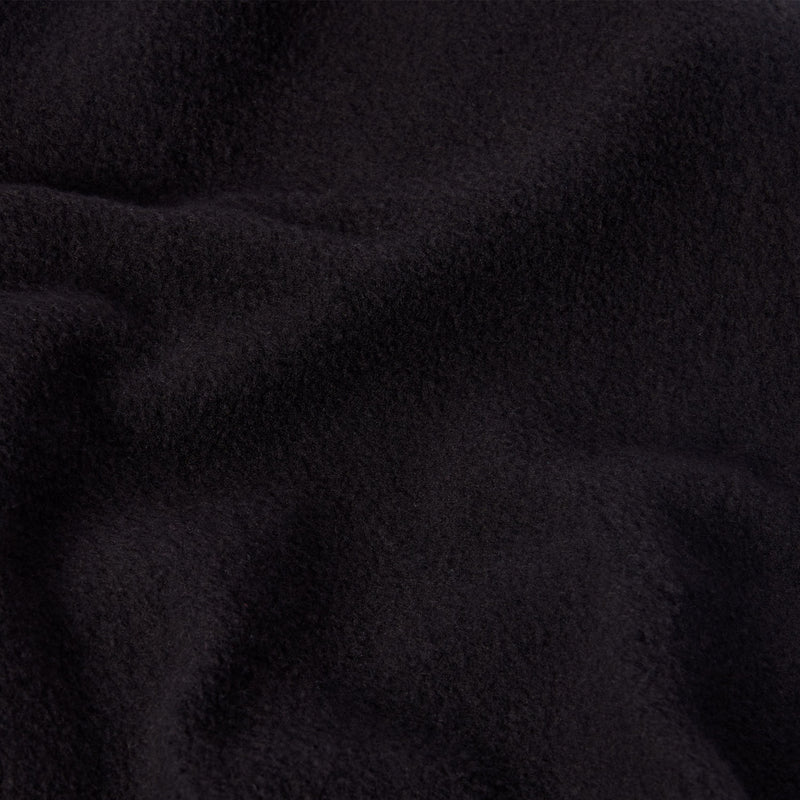 A close-up of soft, black fleece fabric, commonly found in Champion Women’s Knitted Flare Pants, highlighting its textured surface and gentle folds.