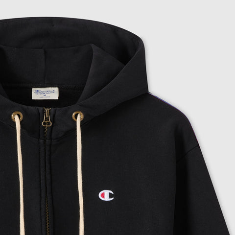 Close-up of the Champion Women’s Icon Hooded Full Zip Sweatshirt in black, featuring cream drawstrings, a full-length zipper, and the embroidered Champion logo on the chest. Made from heavyweight fleece, this hoodie has a visible tag inside the collar.