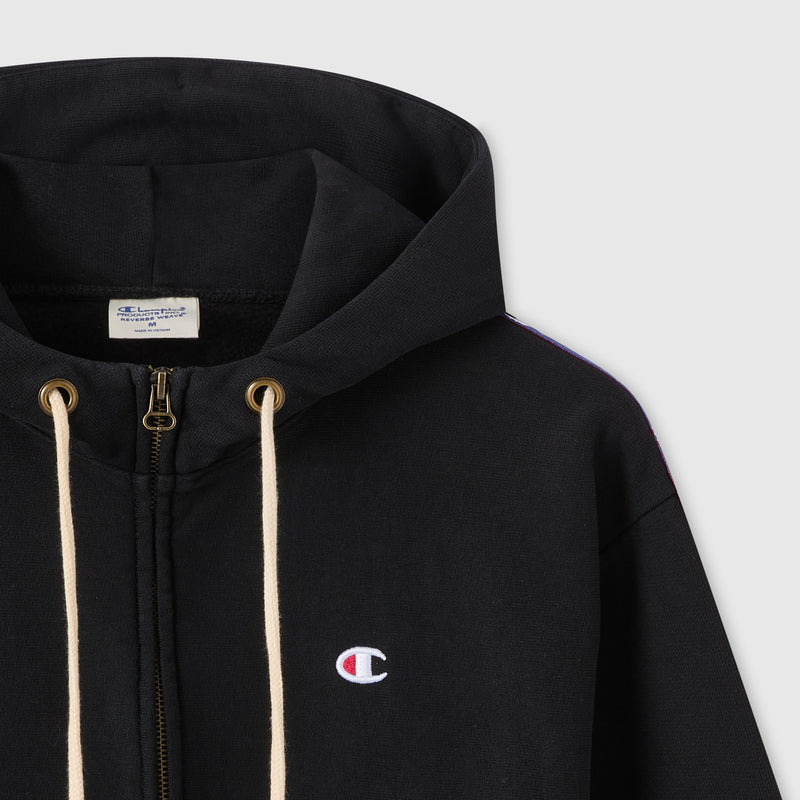 Close-up of the Champion Women’s Icon Hooded Full Zip Sweatshirt in black, featuring cream drawstrings, a full-length zipper, and the embroidered Champion logo on the chest. Made from heavyweight fleece, this hoodie has a visible tag inside the collar.