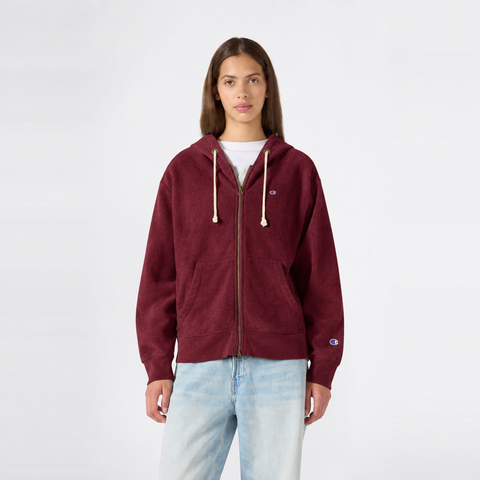A person wearing a maroon Champion Women’s Knitted Hooded Full Zip Sweatshirt with a small logo on the chest and light blue jeans stands against a plain white background, facing forward.