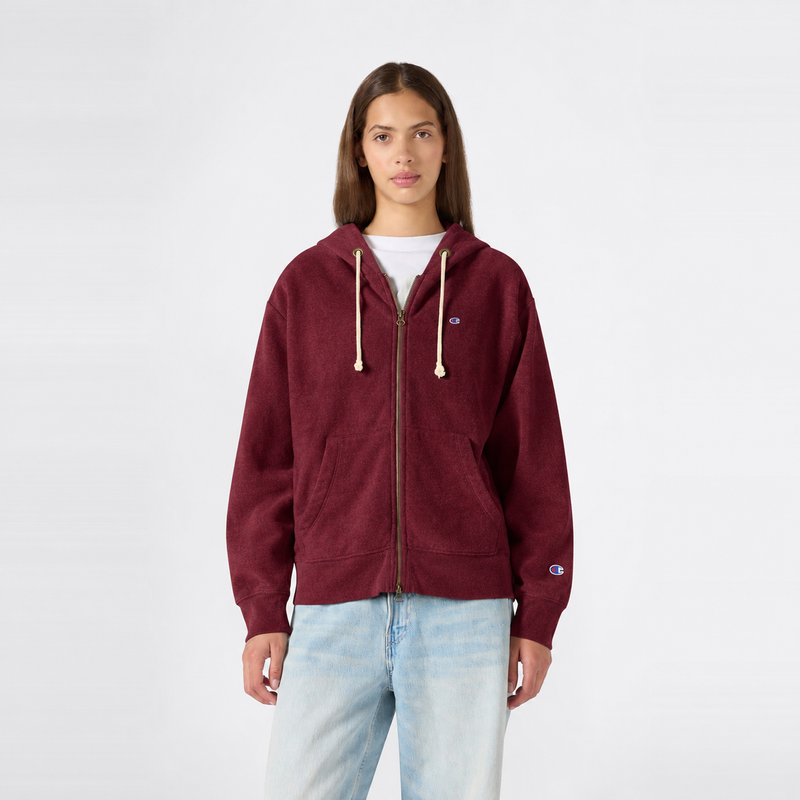 A person wearing a maroon Champion Women’s Knitted Hooded Full Zip Sweatshirt with a small logo on the chest and light blue jeans stands against a plain white background, facing forward.