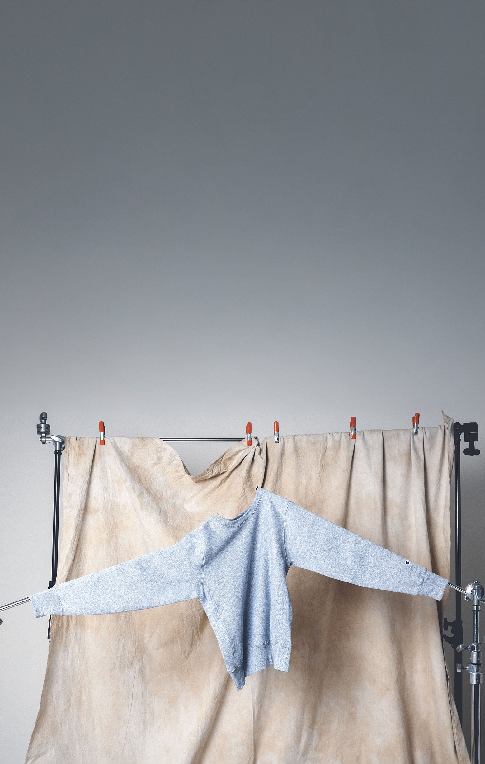 Light blue sweater hanging on a rack against a plain background