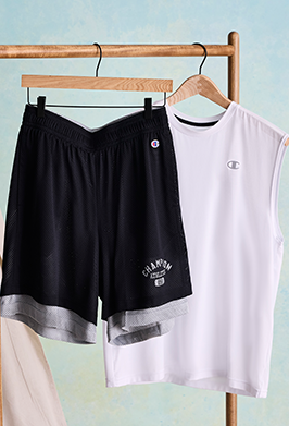 Black shorts and white t-shirt with graphic design on a wooden rack against a light blue background