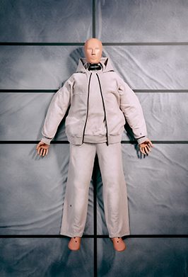 A mannequin or dress form wearing a light beige hooded puffer jacket and matching pants, posed against a dark gray paneled backdrop.