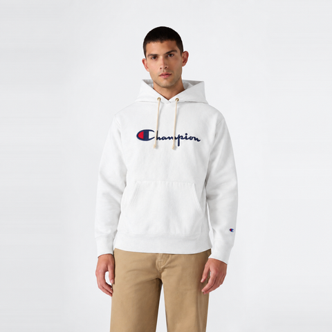 A man wearing a white Champion Men’s Knitted Hooded Sweatshirt featuring an embroidered logo and front pocket, paired with khaki pants, stands facing forward against a plain white background.