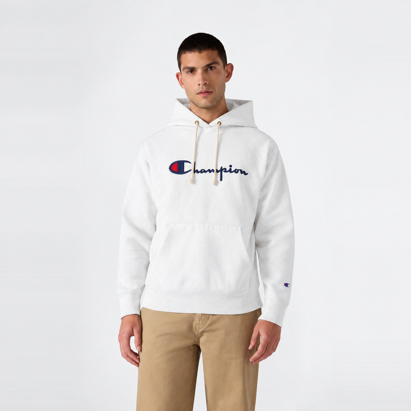 A man wearing a white Champion Men’s Knitted Hooded Sweatshirt featuring an embroidered logo and front pocket, paired with khaki pants, stands facing forward against a plain white background.