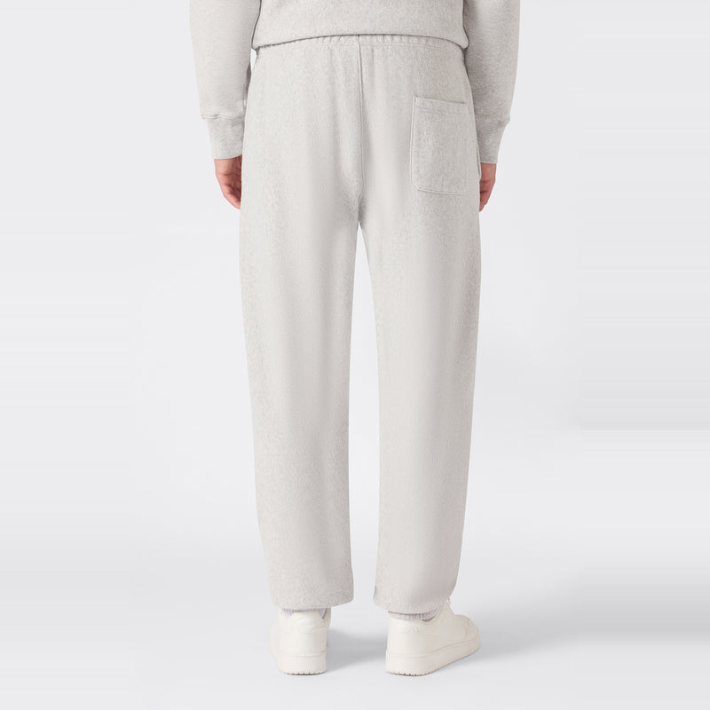 A person is shown from the back wearing light gray Champion Men’s Knitted Elastic Cuff Pants and white sneakers. The pants feature an elastic waistband and a single back pocket. The background is plain white.