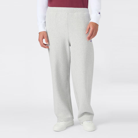 A person is shown from the waist down wearing Champion Men’s Knitted Wide Leg Pants in light gray, paired with a white long-sleeve shirt, a red vest, and white sneakers, standing against a plain white background.