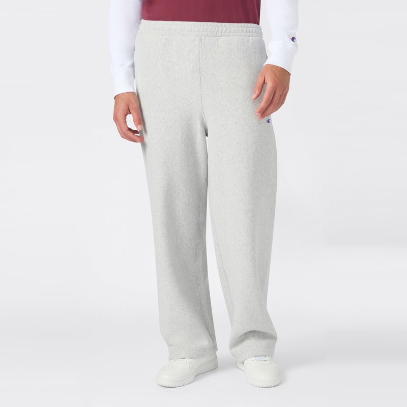A person is shown from the waist down wearing Champion Men’s Knitted Wide Leg Pants in light gray, paired with a white long-sleeve shirt, a red vest, and white sneakers, standing against a plain white background.