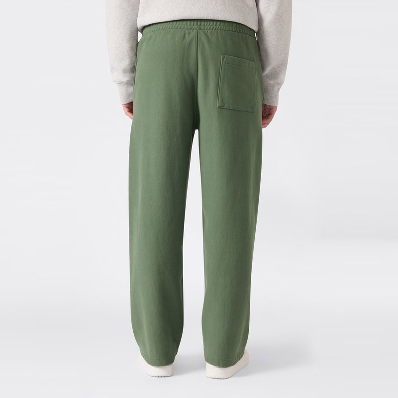 A person is shown from the waist down and viewed from behind, wearing loose-fitting green Men’s Knitted Wide Leg Pants by Champion, featuring a single back pocket and standing against a plain white background.