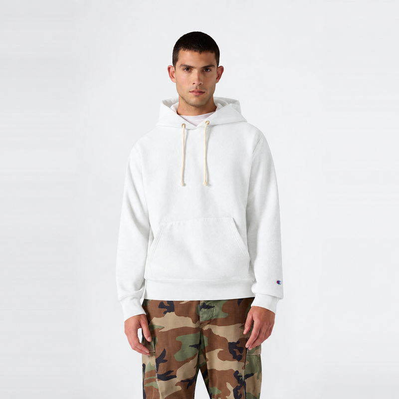 A man stands facing forward wearing a white Champion Men’s Knitted Half Zip Sweatshirt, paired with camouflage pants, against a plain white background.