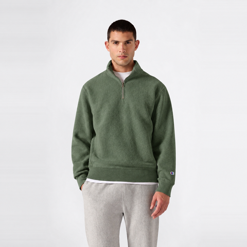 A person wears a green Men’s Knitted Half Zip Sweatshirt by Champion over a white t-shirt and light gray sweatpants, standing against a plain white background.