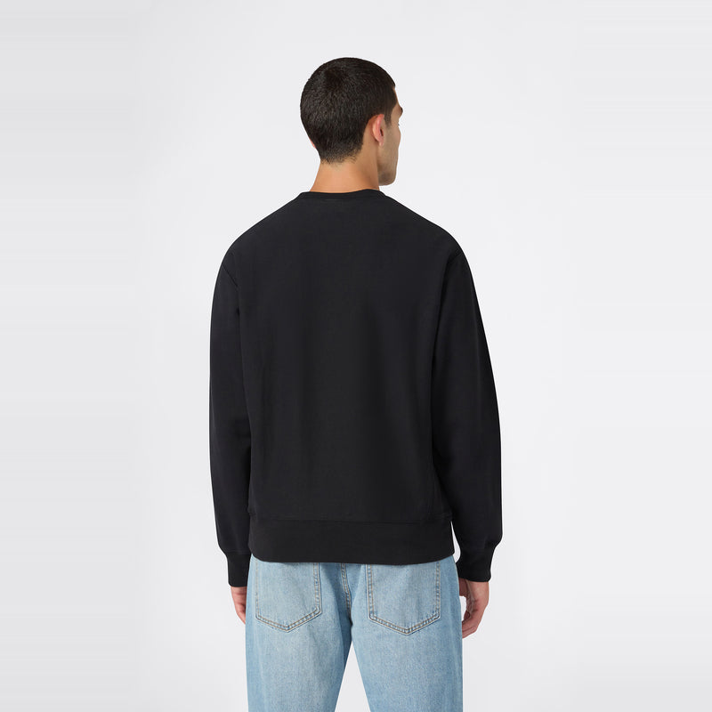 A person stands facing away from the camera, wearing the Men’s Knitted Crewneck Sweatshirt by Champion in black and light blue jeans against a plain white background.