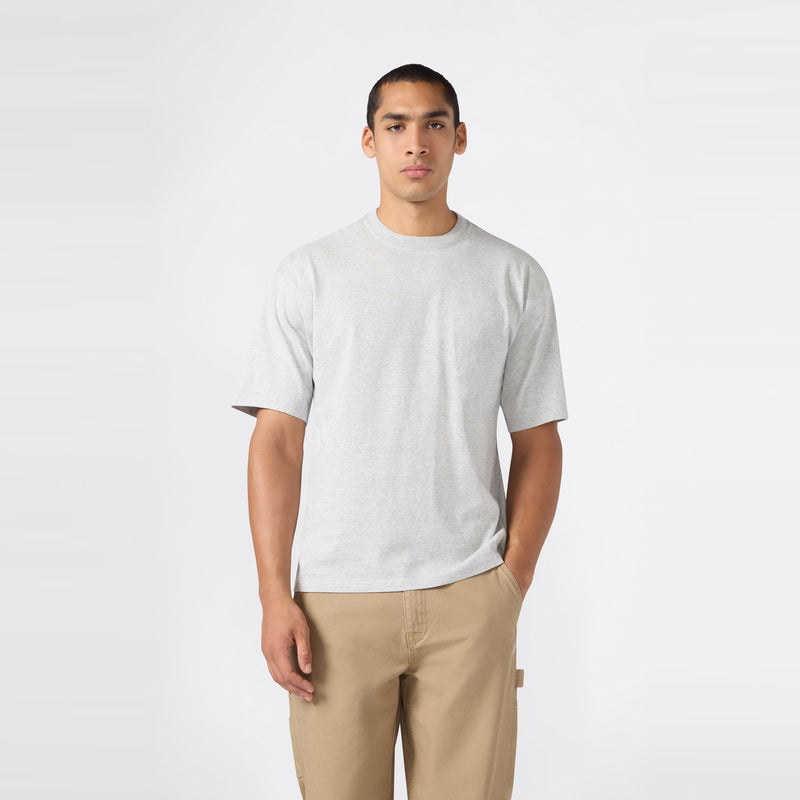 A man stands against a plain white background, wearing the Champion Men’s Knitted T-Shape Tee paired with khaki pants, one hand in his pocket and a neutral expression—perfectly embodying the effortless style of modern men’s sportswear.