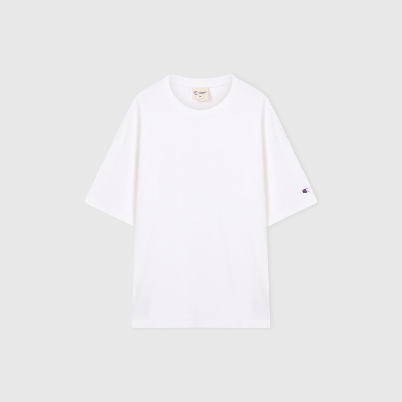 A Men’s Knitted T-Shape Tee by Champion is laid flat on a light gray background. Crafted from heavyweight cotton, this sportswear essential features a small embroidered Champion logo on the left sleeve and a visible neck tag inside the collar.