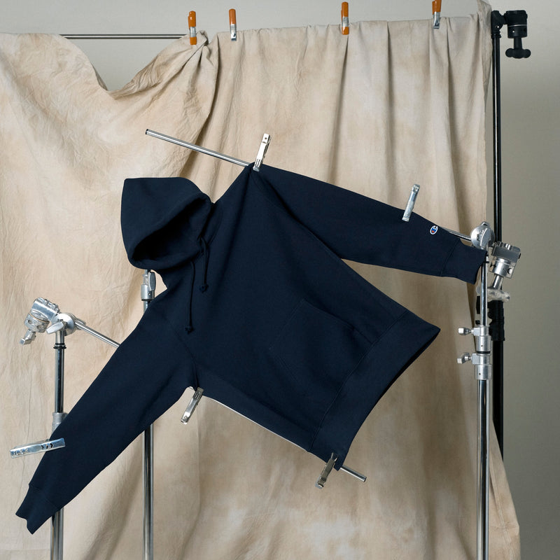Navy hoodie on a stand against a beige curtain background