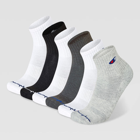 Six Champion Men’s Cushion High Quarter socks in white, black, dark gray, and light gray stand upright on a plain light gray background. Each features Champion branding near the toe and logo on the ankle.