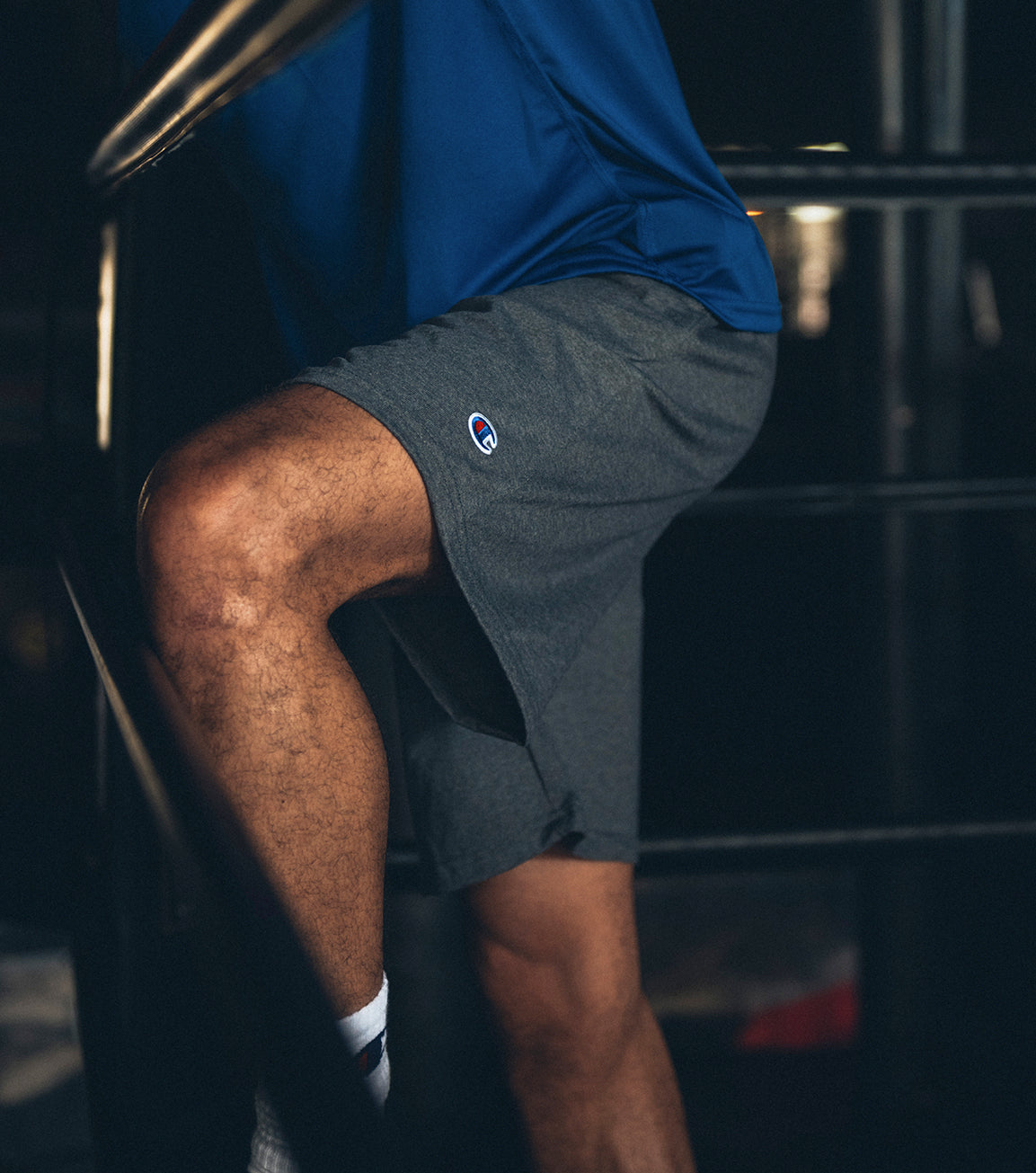 Person wearing dark gray shorts with a logo on a blurred background