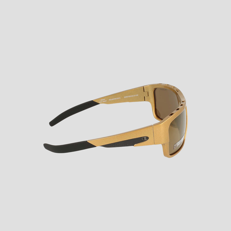 Side view of the Champion Men's Polarized Grilamid Flex Grip Tip - Large sunglasses, featuring gold frames with thick black temple tips and brown-tinted polarized lenses. Set against a plain light background, these sunglasses showcase a sporty, angular design for lightweight comfort.