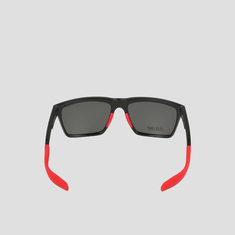 Men's Polarized Grilamid Flex Grip Tip - Medium sunglasses by Champion, shown from the back. Featuring a sleek black frame with rectangular dark lenses, these shades stand out with bright red temple tips and accents along the arms for a bold contrast. Crafted from lightweight TR90 Grilamid, this RX-able frame is designed for comfortable everyday wear. Set against a plain light gray background.