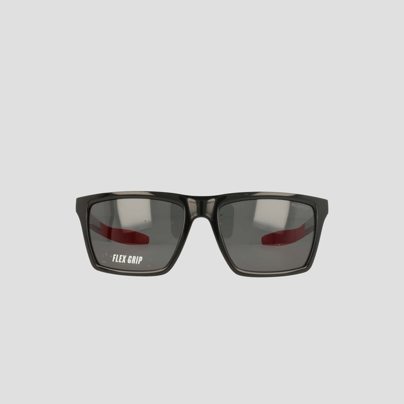 Black sunglasses with rectangular, polarized lenses and a slight reflection, featuring the text FLEX GRIP on the left lens. The lightweight, RX-able TR90 Grilamid frame from Champion's Men's Polarized Grilamid Flex Grip Tip - Medium is positioned against a plain light gray background.