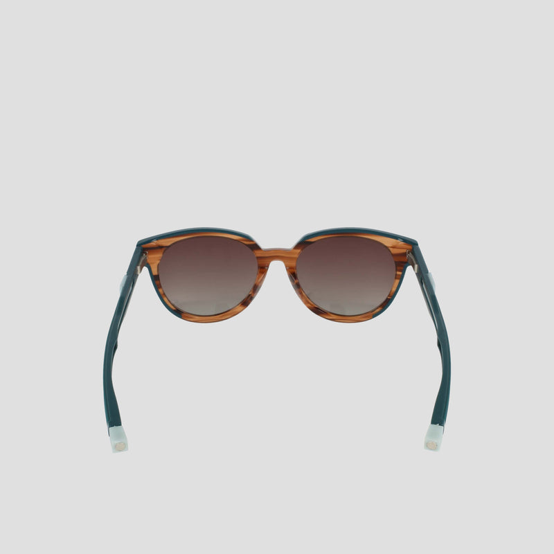 Champion Women's Polarized Retainer Round sunglasses feature brown tortoiseshell round frames, dark gradient polarized lenses, and teal-blue arms with white tips, shown against a light gray background.