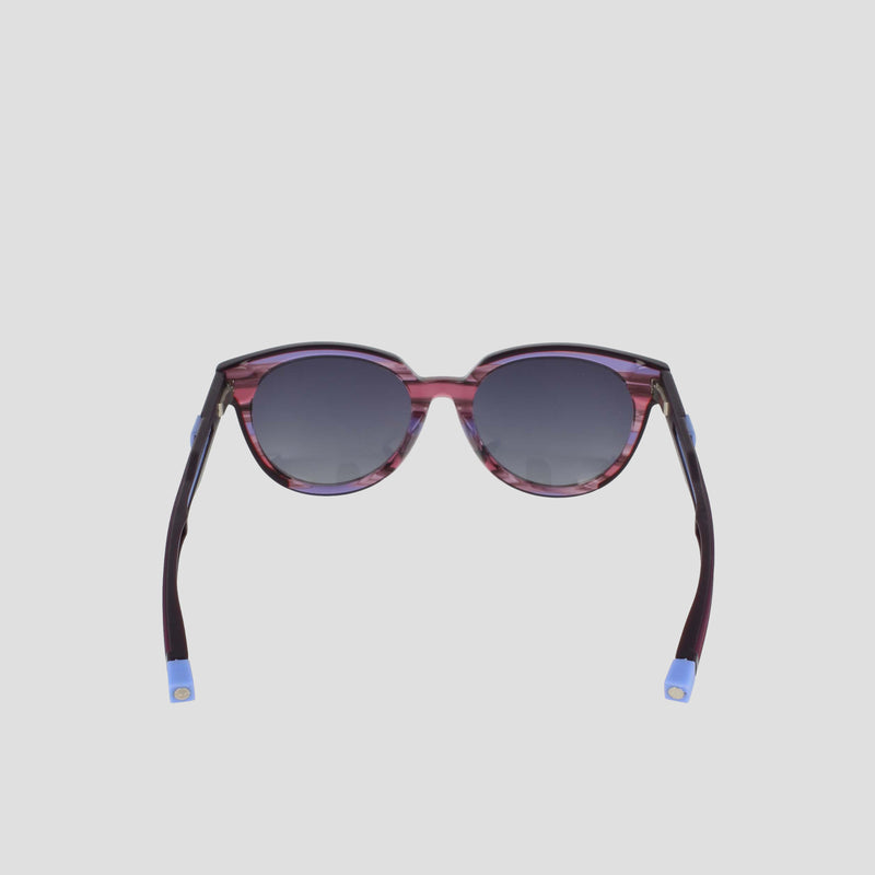 The Champion Women's Polarized Retainer Round features purple frames, dark gradient lenses, and blue-tipped arms, shown against a simple light gray background.