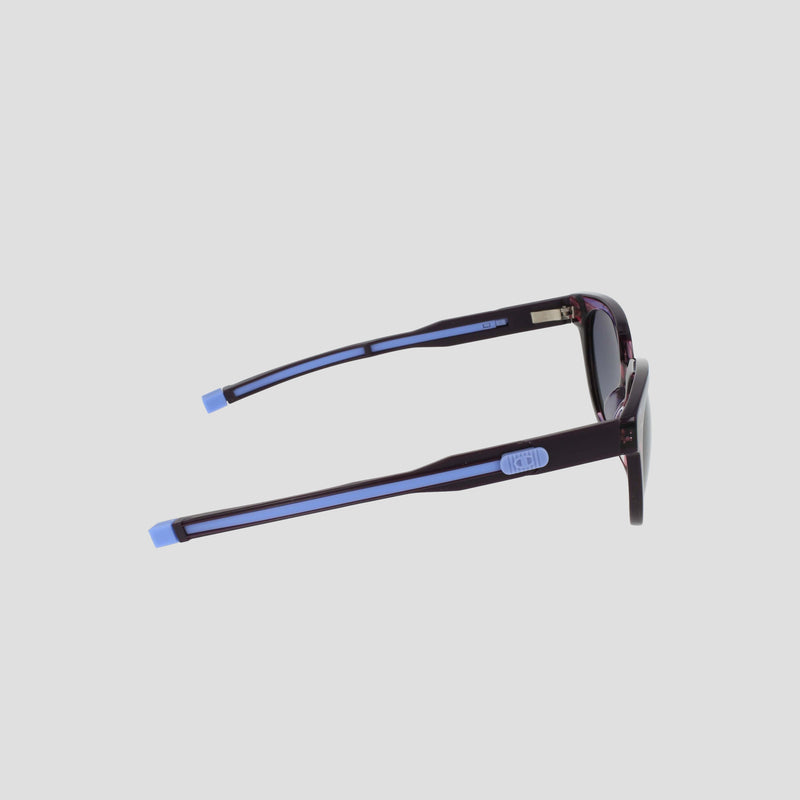 Side view of Champion Women's Polarized Retainer Round sunglasses featuring dark frames with light blue accents on the temple tips and arms, perfect for elevating women’s fashion eyewear against a plain light background.