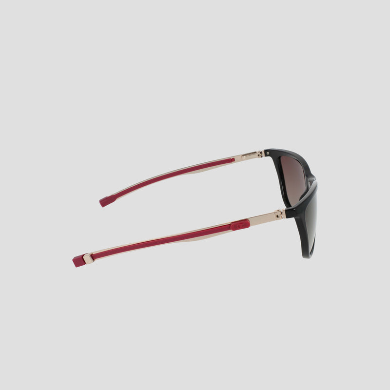 The Champion Women's Polarized Retainer Rectangle sunglasses are displayed from the side on a plain white background, featuring a black rectangle cateye frame, dark polarized lenses, gold hinges, and bold red arms—an athleisure eyewear statement that merges modern flair with timeless style.