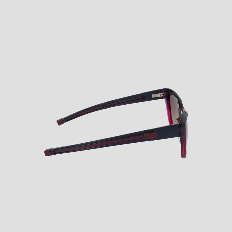 Side view of Champion Women's Polarized Retainer Square sunglasses, featuring bold cateye frames with thick dark blue handmade acetate arms and red accents on the front and edges, set against a plain light gray background.