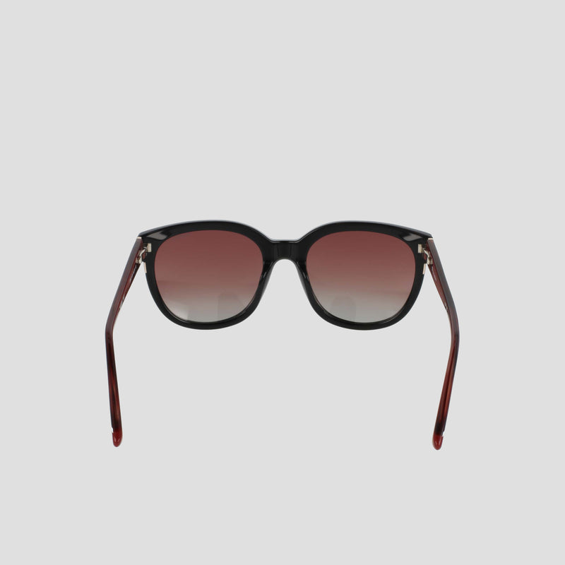 Introducing the Champion Women's Polarized Curvaceous Square sunglasses, crafted from luxury acetate eyewear. These sunglasses feature dark gradient lenses set in bold black frames, with distinctive outward-curving reddish-brown arms. Presented against a plain light gray background, this pair offers both elegance and protection.
