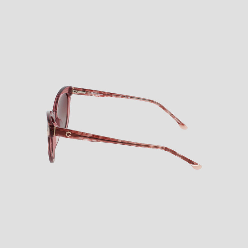 Side view of the Champion Women's Polarized Cateye sunglasses in pink, featuring round, RX-able translucent frames and lightly tinted lenses. The slim arms showcase a subtle gold C detail near the hinge, set against a plain white background.